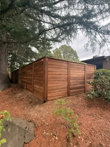 Horizontal cedar fence under a large tree